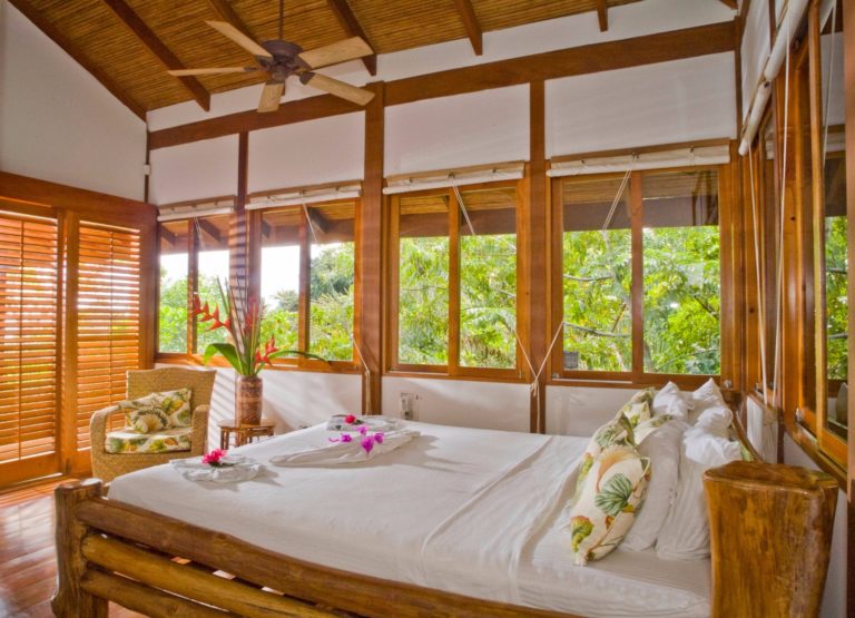 Bedroom with wooden interior and large windows overlooking tropical vegetation in Manuel Antonio Costa Rica