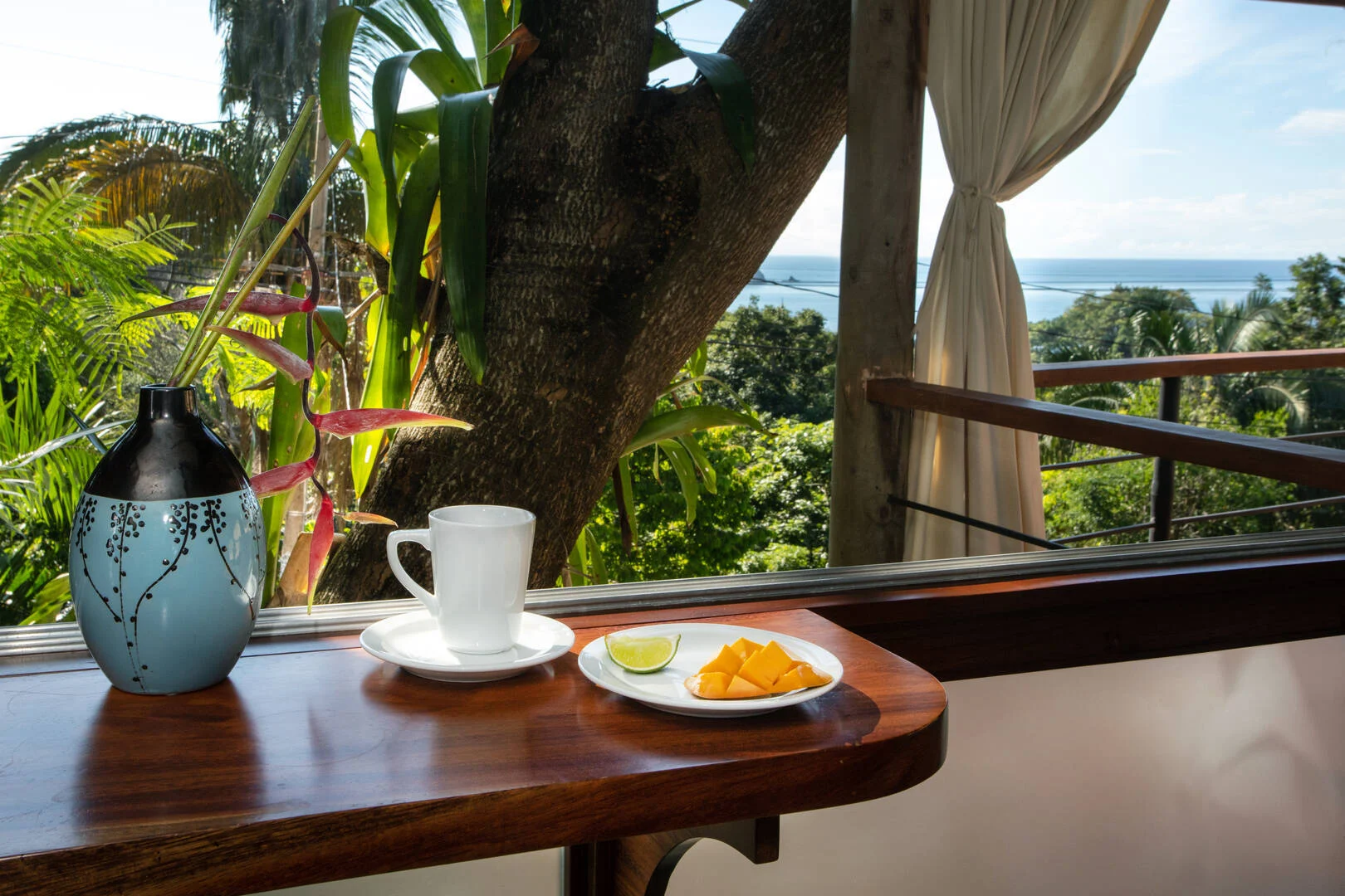 Breakfast bar with fresh tropical fruit and ocean views framed by lush greenery in Manuel Antonio