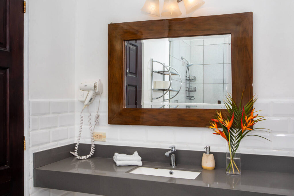 A beautiful wooden framed mirror features in this luxury bathroom with stone counter and metro tiles.