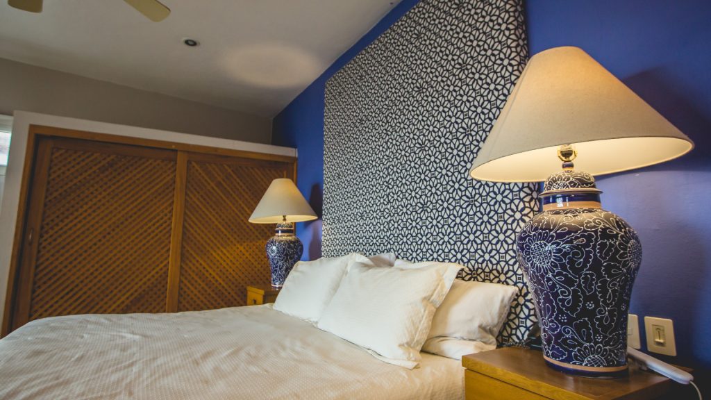 This bed has a decorative blue backboard with matching lamps