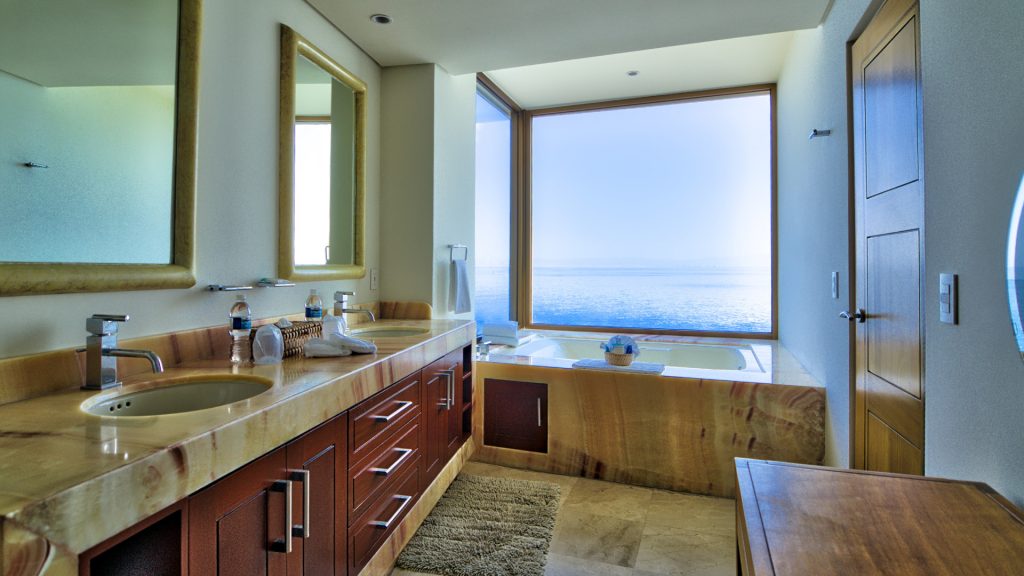 This stunning bathroom with a large winndow also features his and hers sinks .