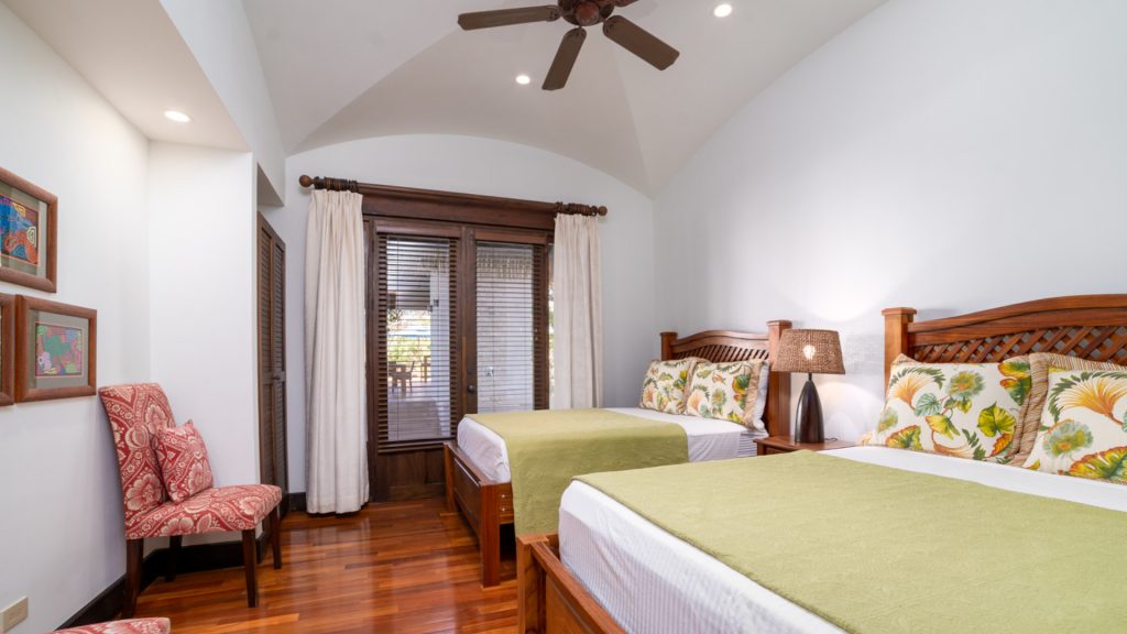 This room includes twin beds with ceiling fans and hardwood flooring.