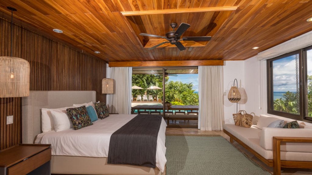 This bedroom with wooden ceilings and walls has a warm relaxing vibe to go with stunning ocean views.