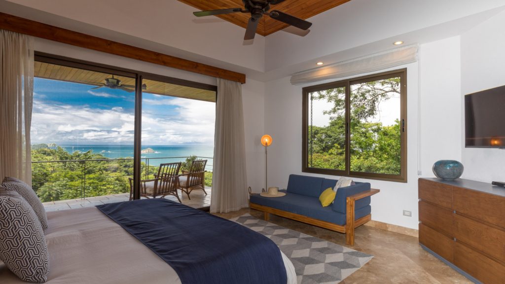 This relaxing bedroom has it all, a place to sit inside, a spot to chill out on the balcony, and an awesome ocean view.