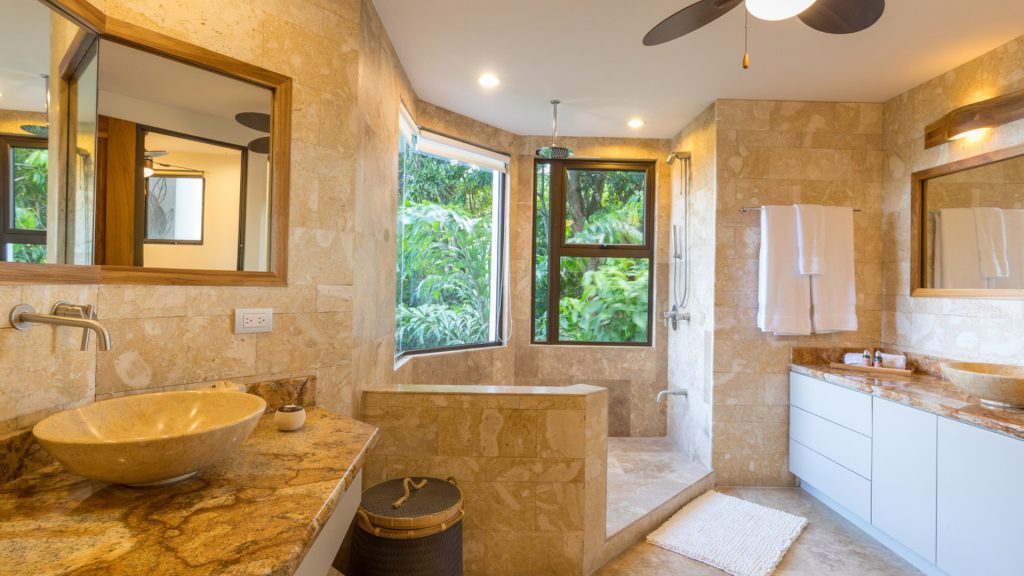 This luxurious bathroom is full of natural stone and the shower surrounded by tropical views.