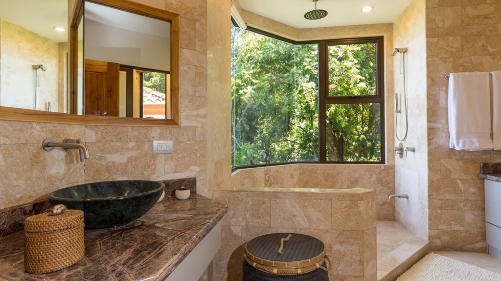 This bathroom has a beautiful natural stone sink and a tropical rain shower surrounded by beautiful views.