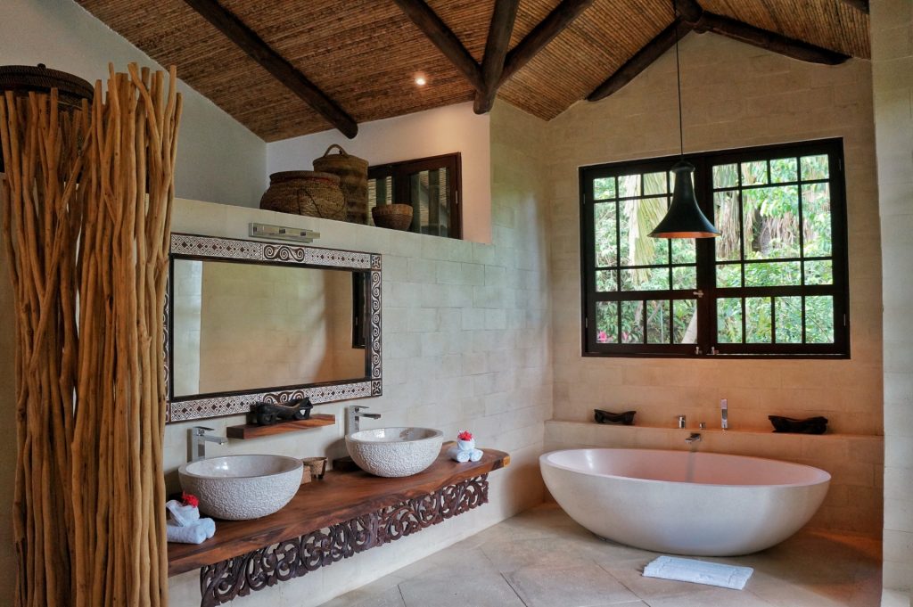The design of this bathroom offers a luxury setting with hand-carved accents, a stone tub, and his and hers sinks. 