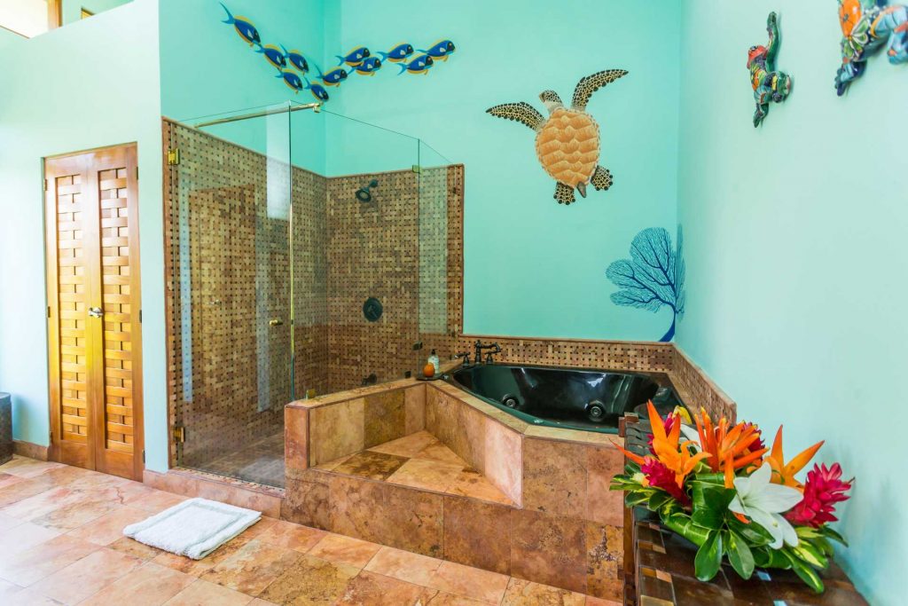 Take a relaxing bubble bath in this incredible master bathroom with colorful wall art, a walk-in closet, and a large shower.