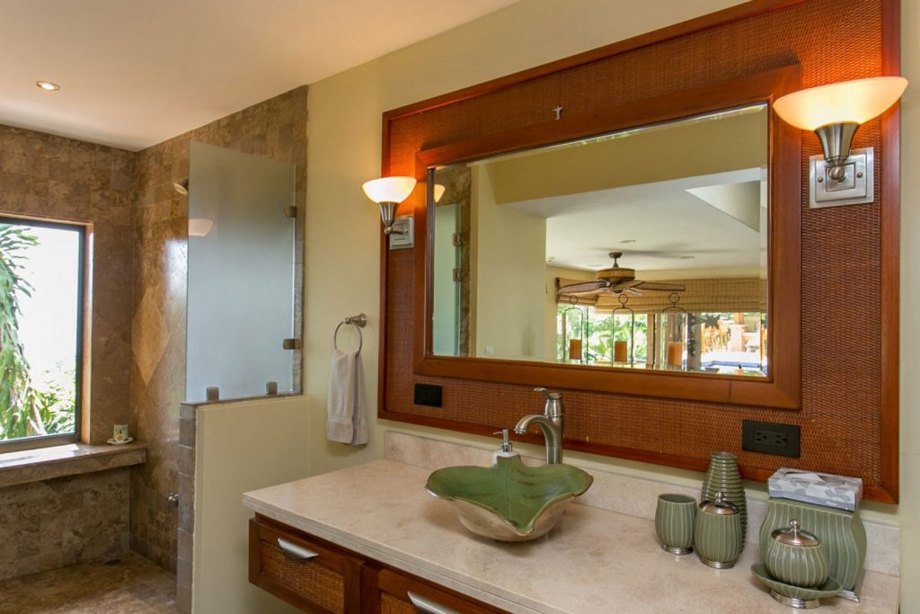 This bathroom features stunning natural tiles and a stone counter, with a handcrafted mirror and sink.