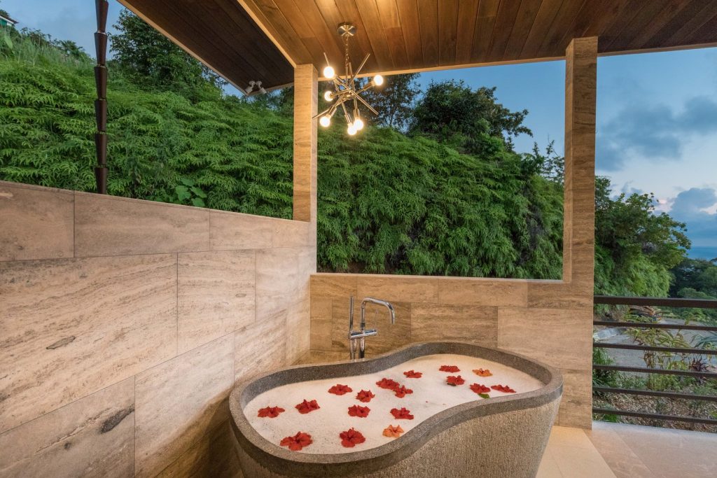 This incredible open-air bathroom features a luxury stone soaking tub.