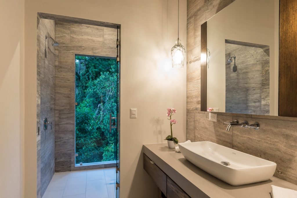 This luxury bathroom has stunning tiles and fixtures with an awesome rainforest view in the shower.