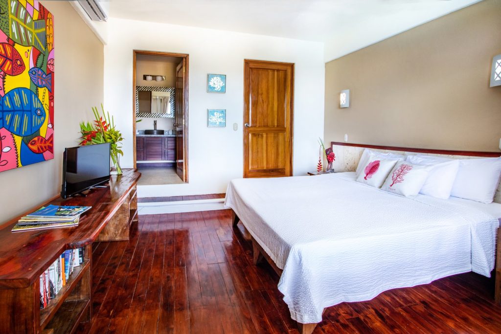 The beautiful master bedroom features an ensuite bathroom, king bed, and a massive ocean and pool view.
