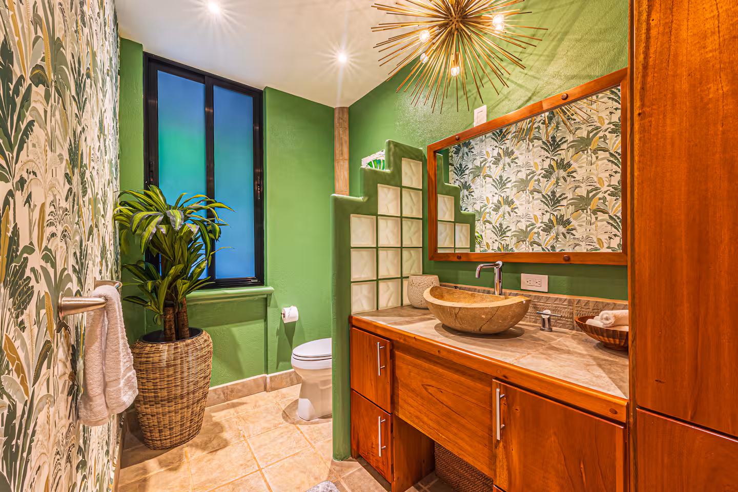 Green tropical bathroom with custom wood vanity, stone sink, and patterned walls in a luxury villa near Dominical, Costa Rica.