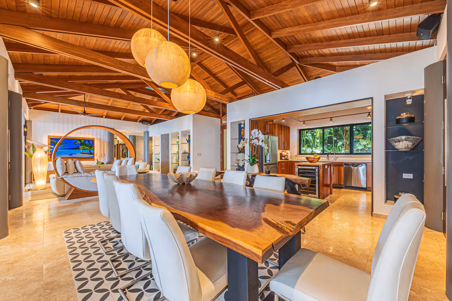 Open-plan dining area with large wood table, living room seating, and kitchen in a luxury villa near Dominical, Costa Rica.