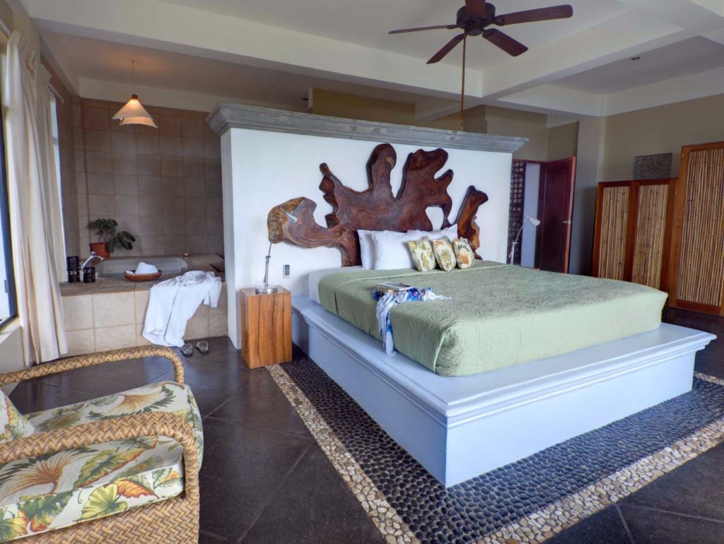 The master bedroom has a unique natural wood headboard and a beautiful native stone floor around the king bed. 