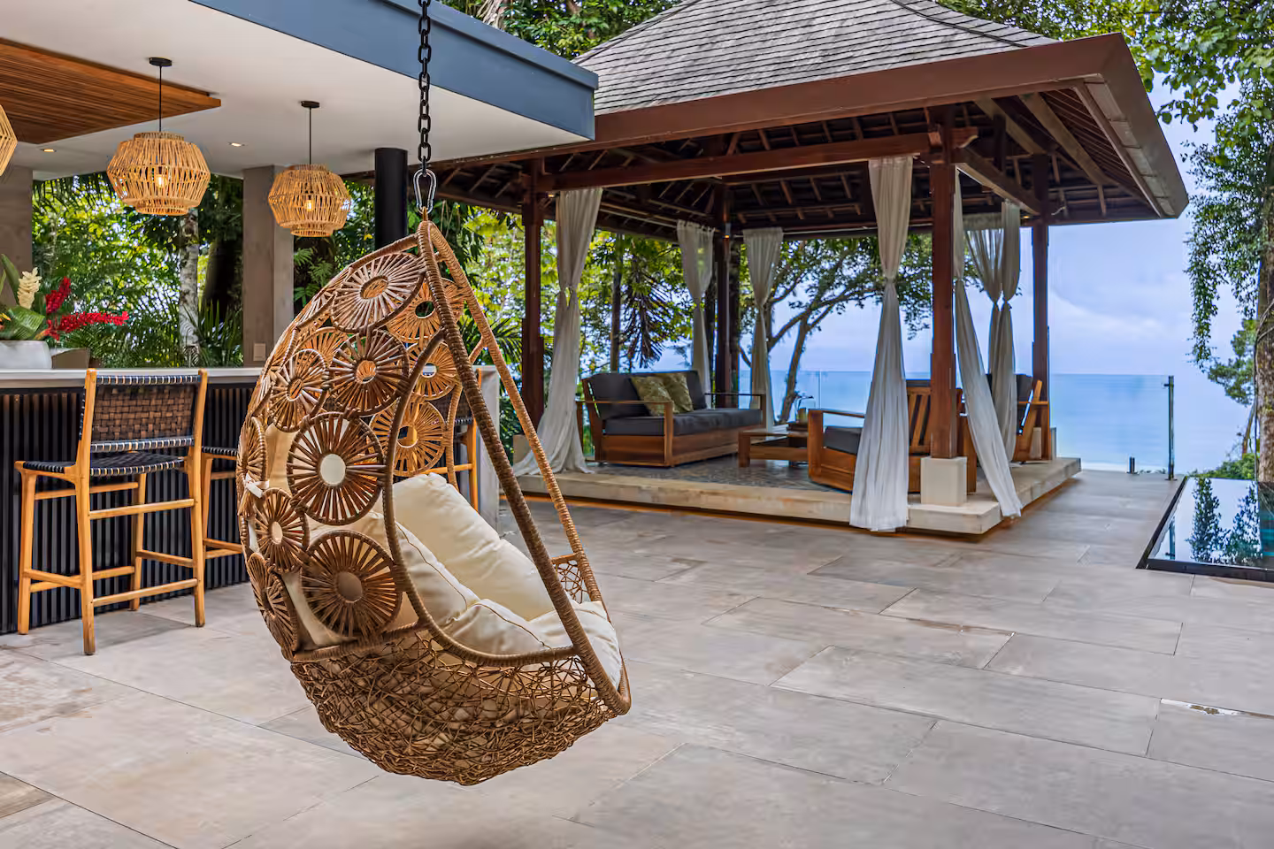 Outdoor bar area with hanging chair and shaded gazebo overlooking the ocean at a luxury villa near Dominical, Costa Rica.
