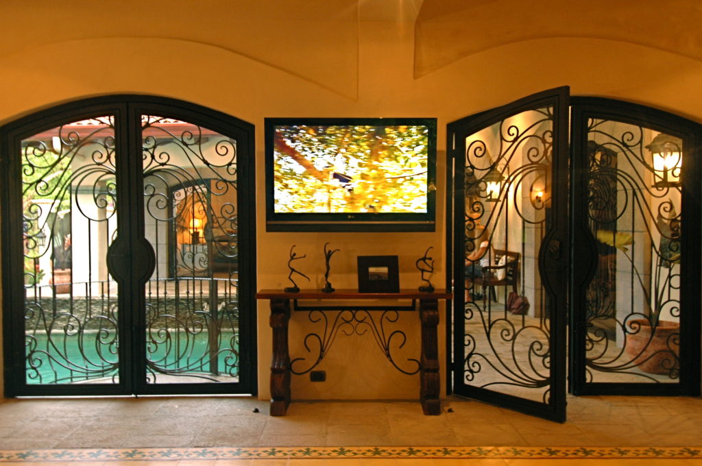 Elegant wrought iron double doors, embraced by glass, illuminate the villa with natural light and add a touch of sophistication.