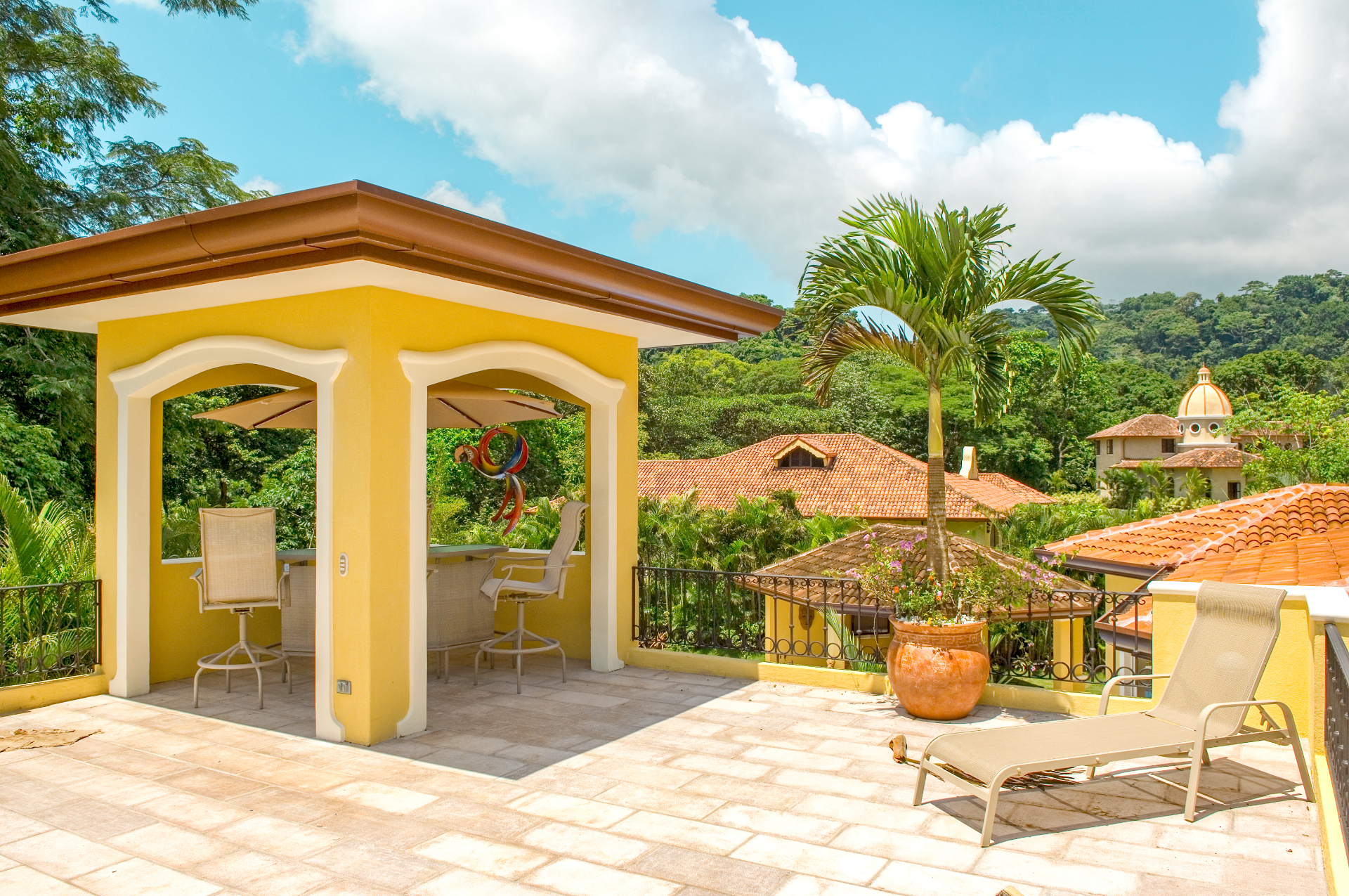 Private rooftop terrace with shaded seating overlooking Los Sueños villas and tropical hillsides.