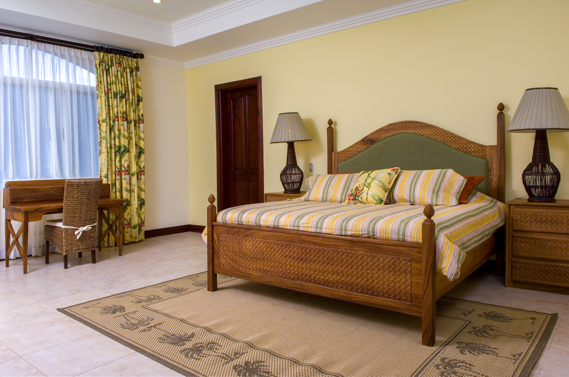 King bedroom with wood furnishings and desk beside the window.