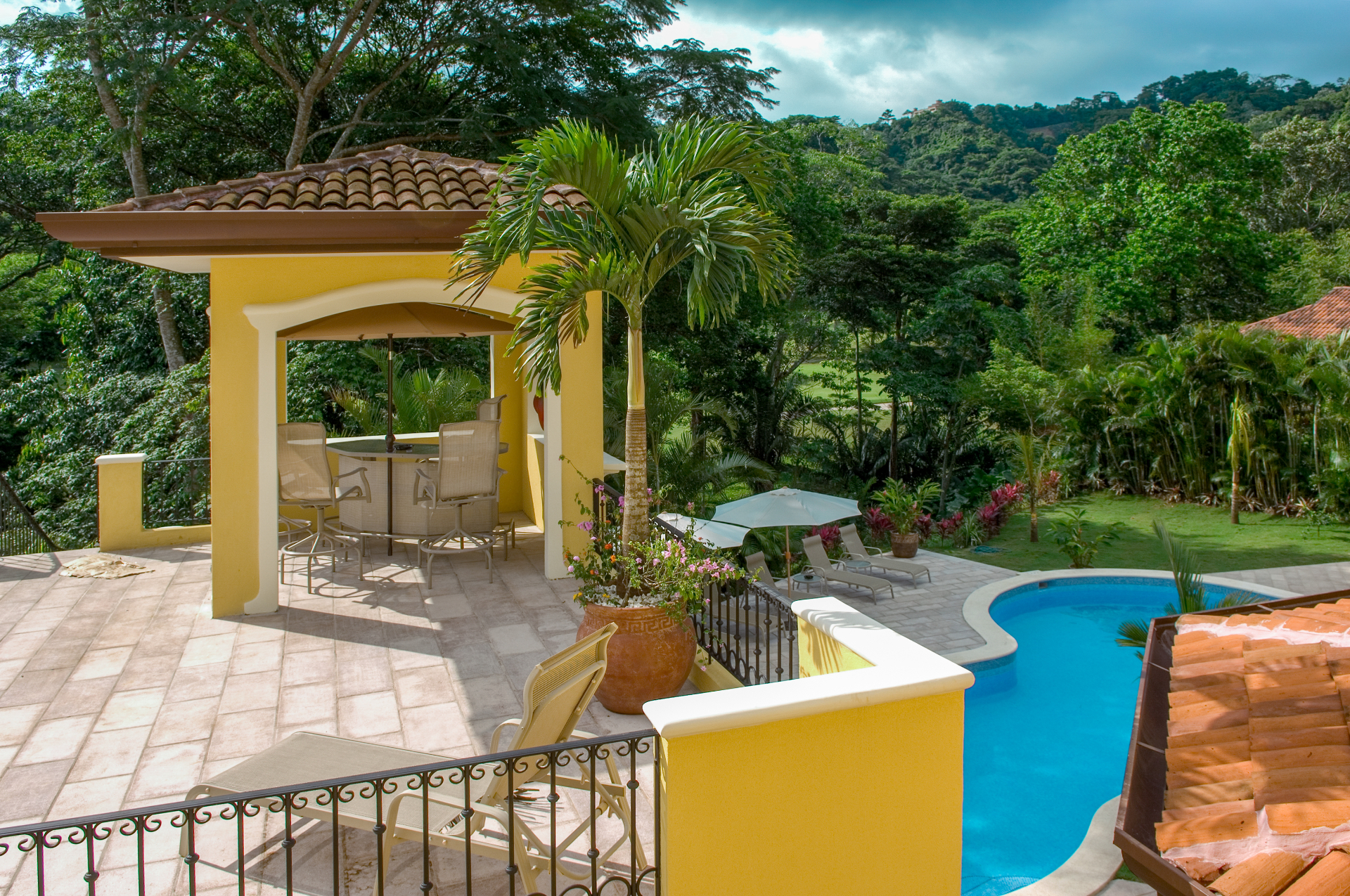 Covered terrace with outdoor seating overlooking the villa pool and tropical gardens.