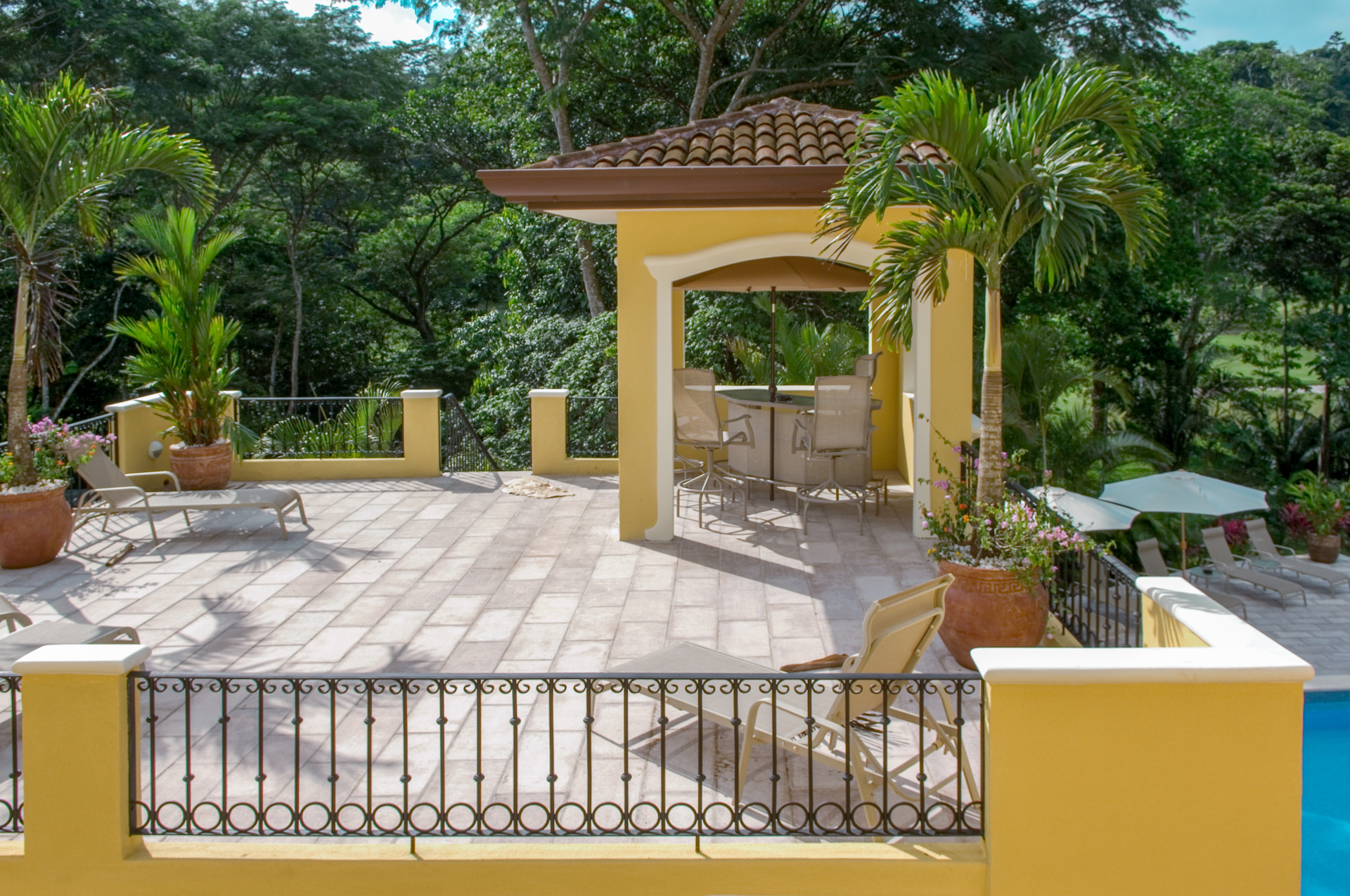 Elevated terrace with loungers and covered gazebo overlooking tropical greenery.