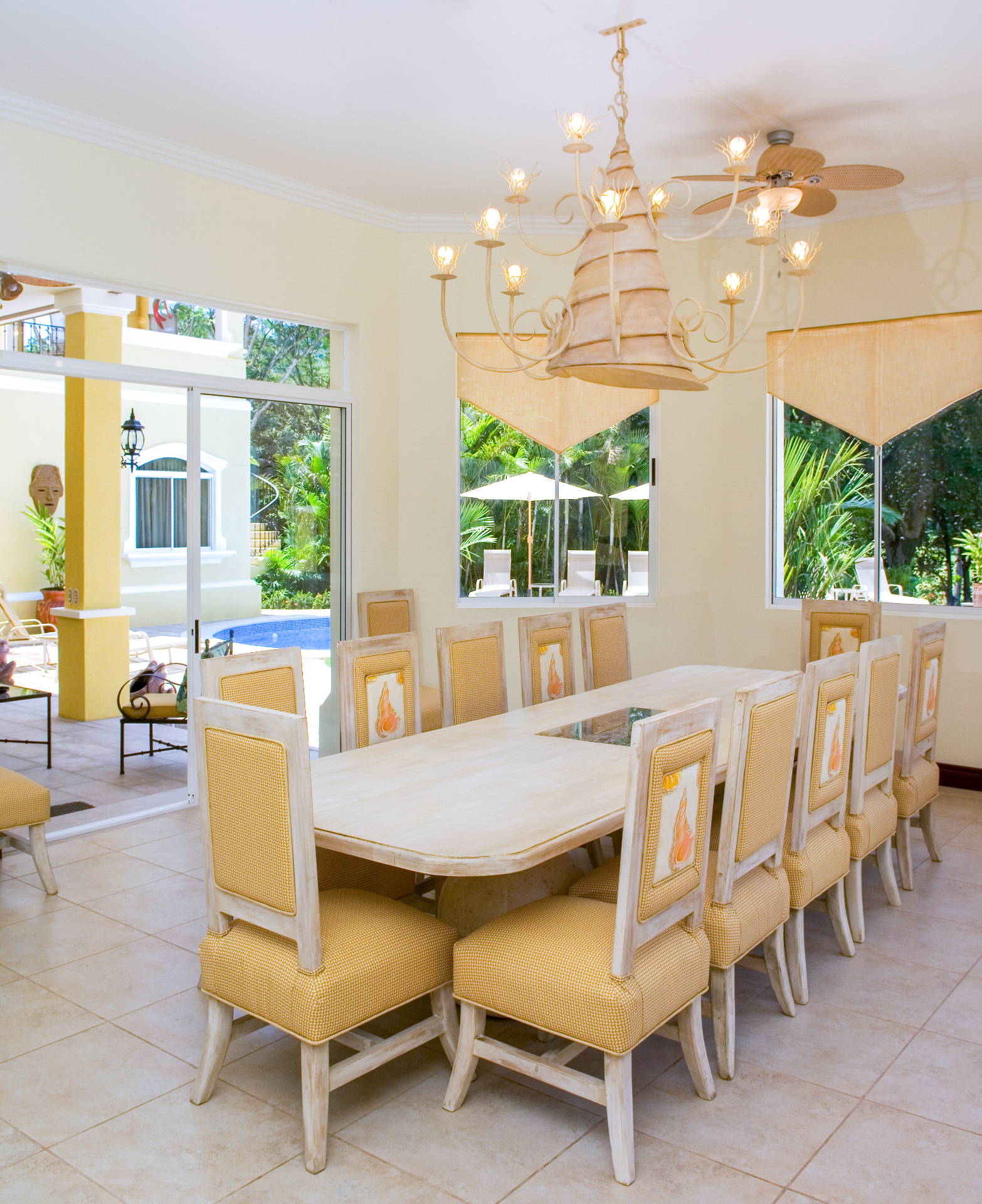 Villa dining room with table for fourteen guests and wide sliding doors opening to the pool terrace.