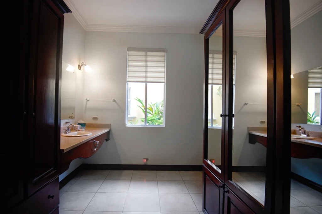 A bright ensuite bathroom with a wide vanity counter and natural light from a garden-facing window.