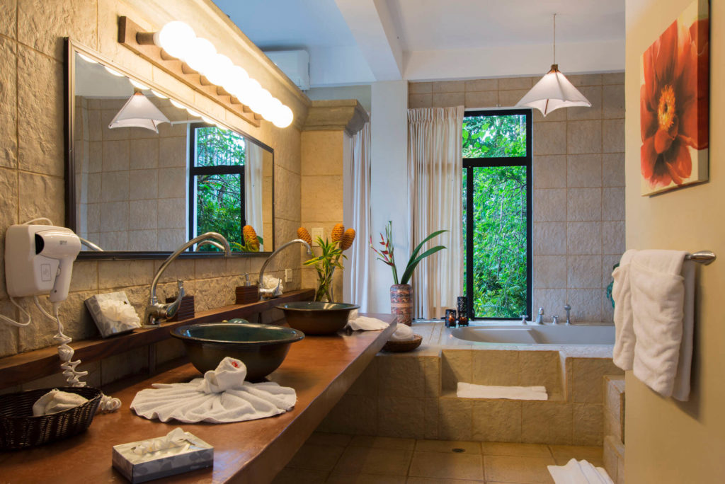 Luxury bathroom with stone finishes, double sinks, and bathtub surrounded by tropical greenery in Manuel Antonio Costa Rica