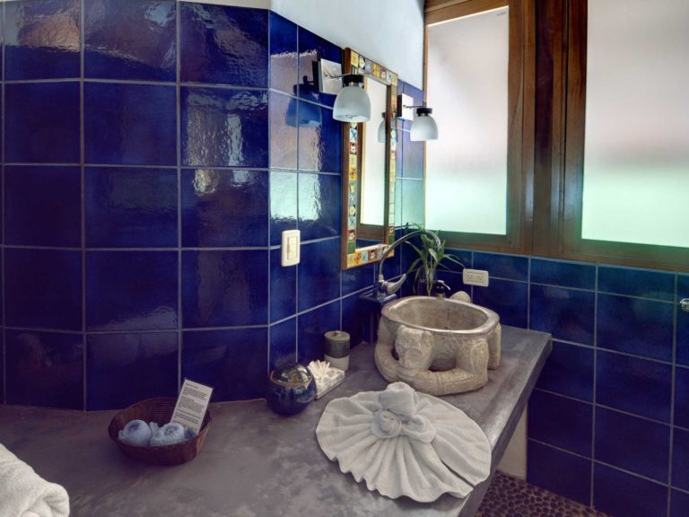 Bathroom with blue tile walls, stone sink, and vanity in Manuel Antonio Costa Rica