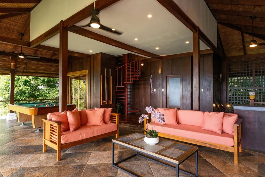 A spacious open-air lounge designed for gathering, with warm wood finishes and views into the surrounding greenery.