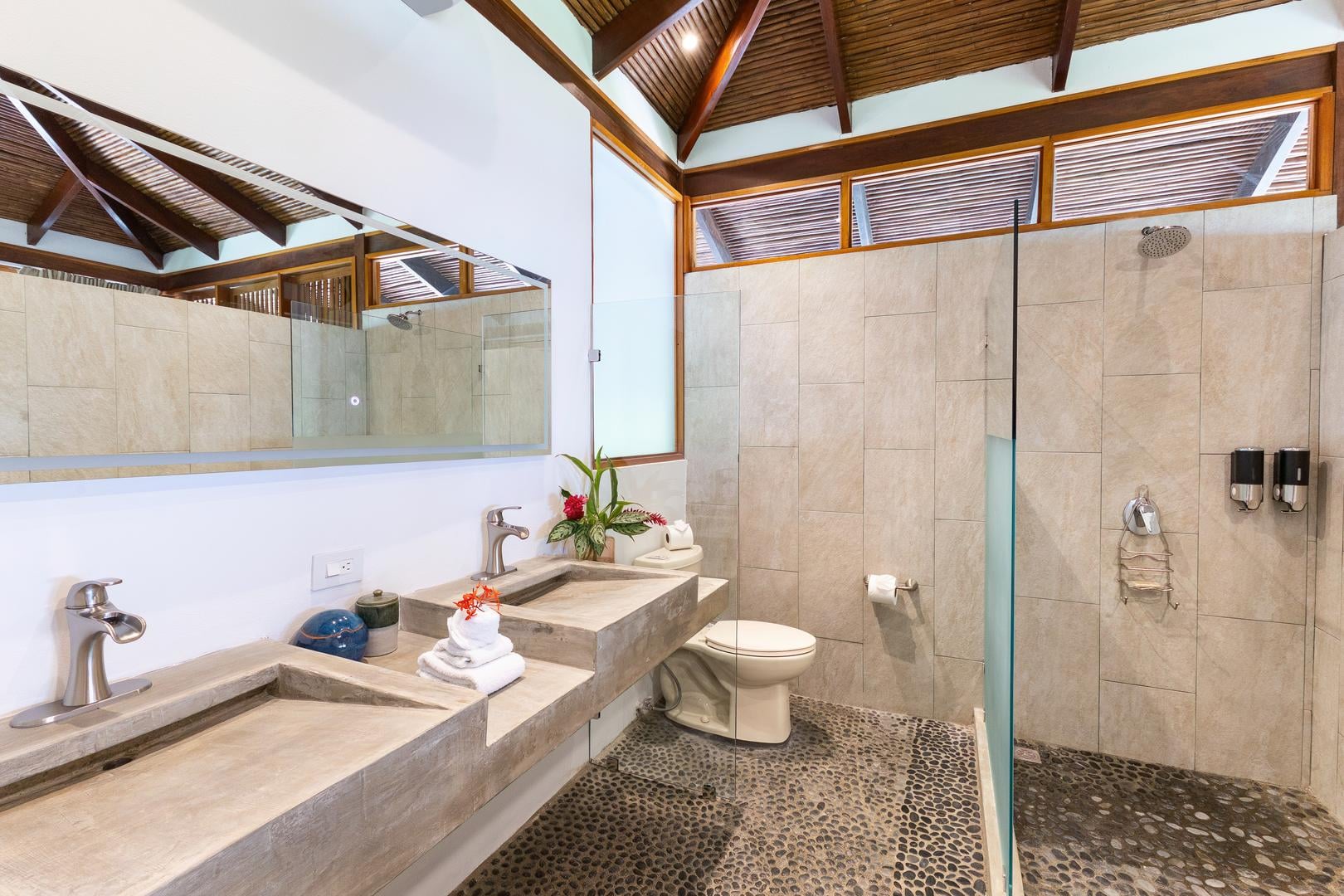 Double vanity bathroom with stone sinks and walk-in shower in a luxury Manuel Antonio villa