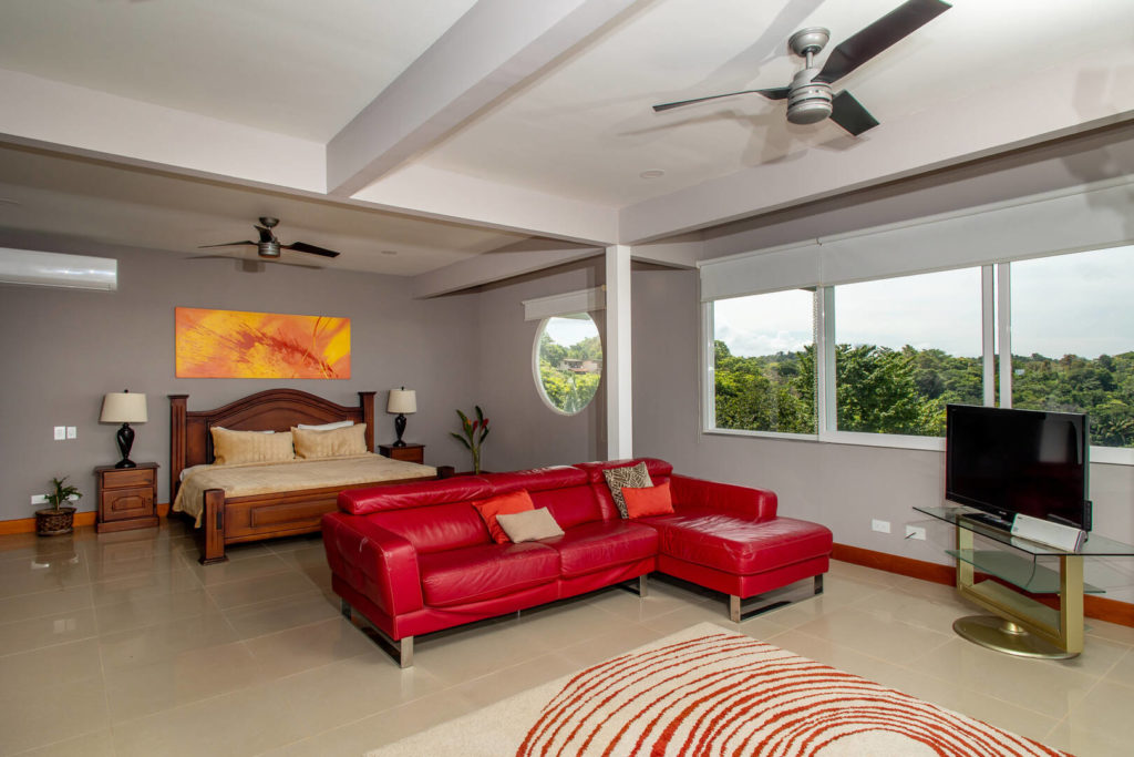 Relax in this expansive bedroom with a stylish seating area equipped with a large-screen TV.