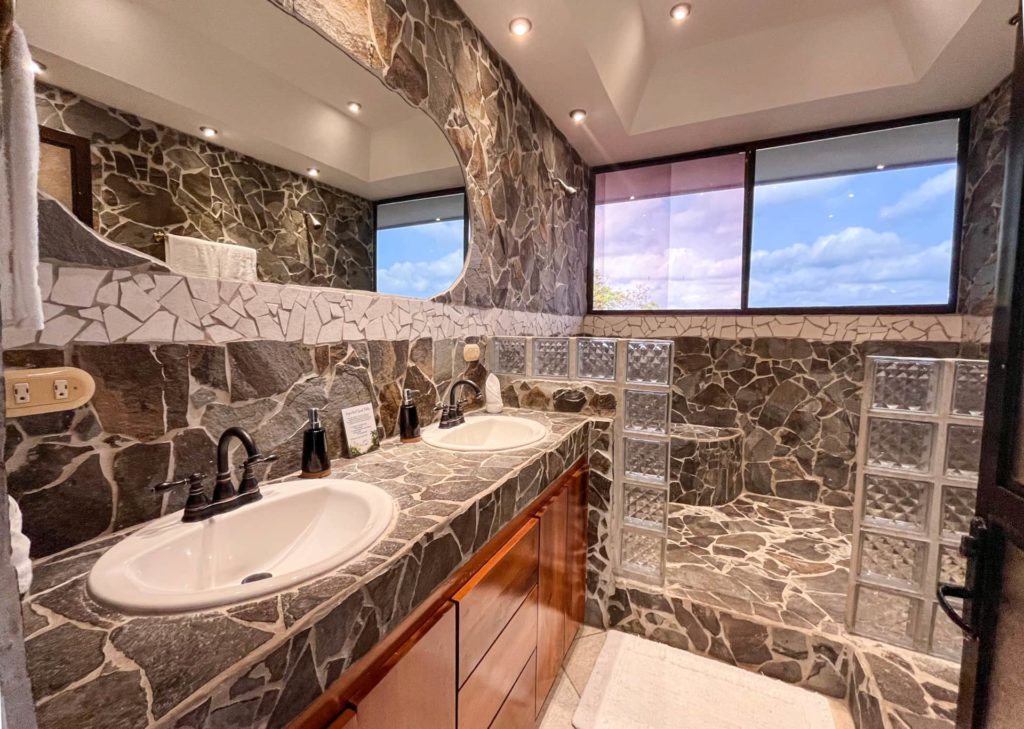 Featuring his and hers sinks, this bathroom showcases exquisite tiles and wooden accents, adding to its charm and elegance.