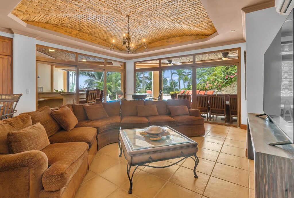 A spacious family room with comfortable seating opens directly to the outdoor terraces, creating a seamless connection between indoor comfort and beachfront living on Costa Rica's Nicoya Peninsula.