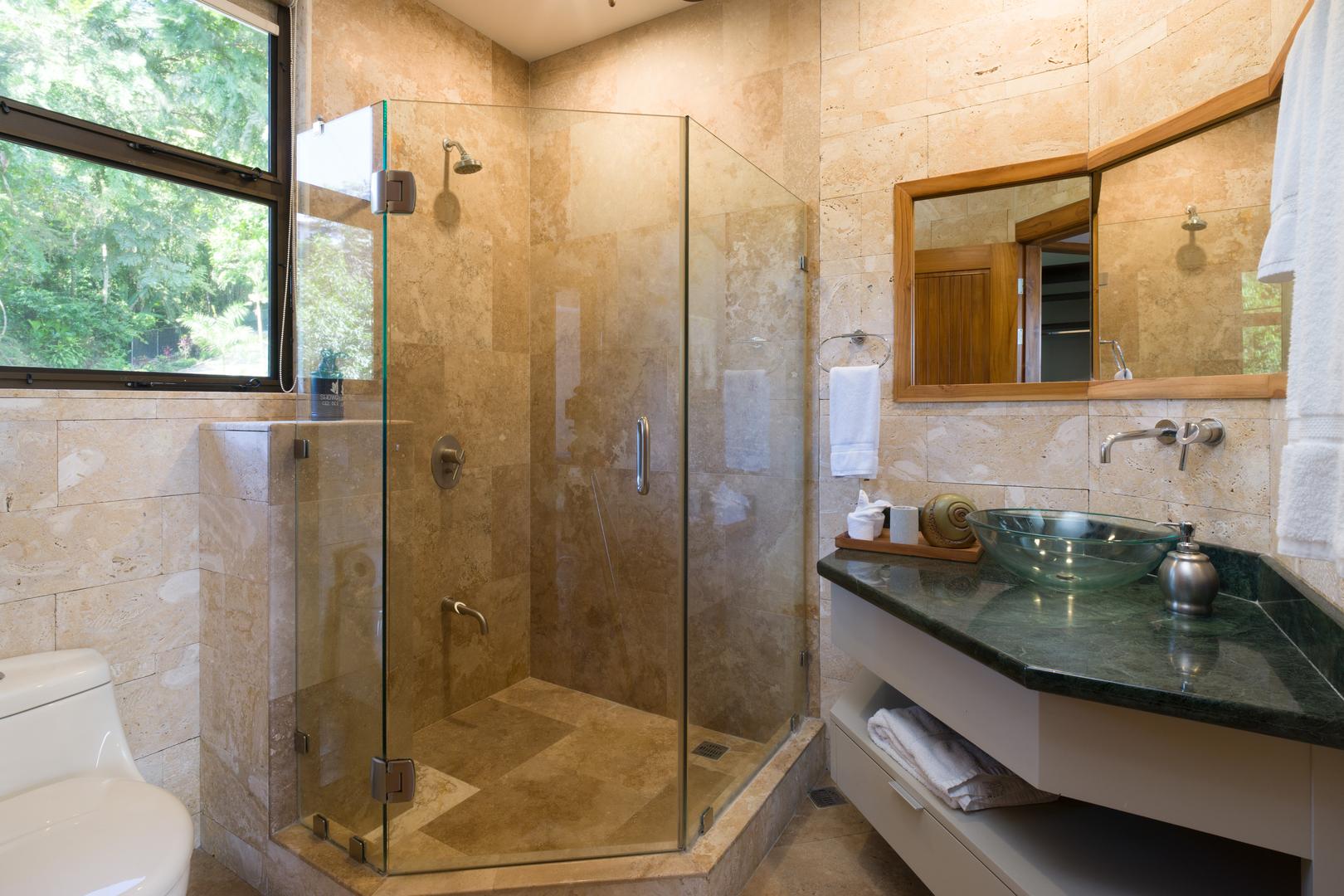 modern-stone-bathroom-with-glass-shower-and-greenery-view