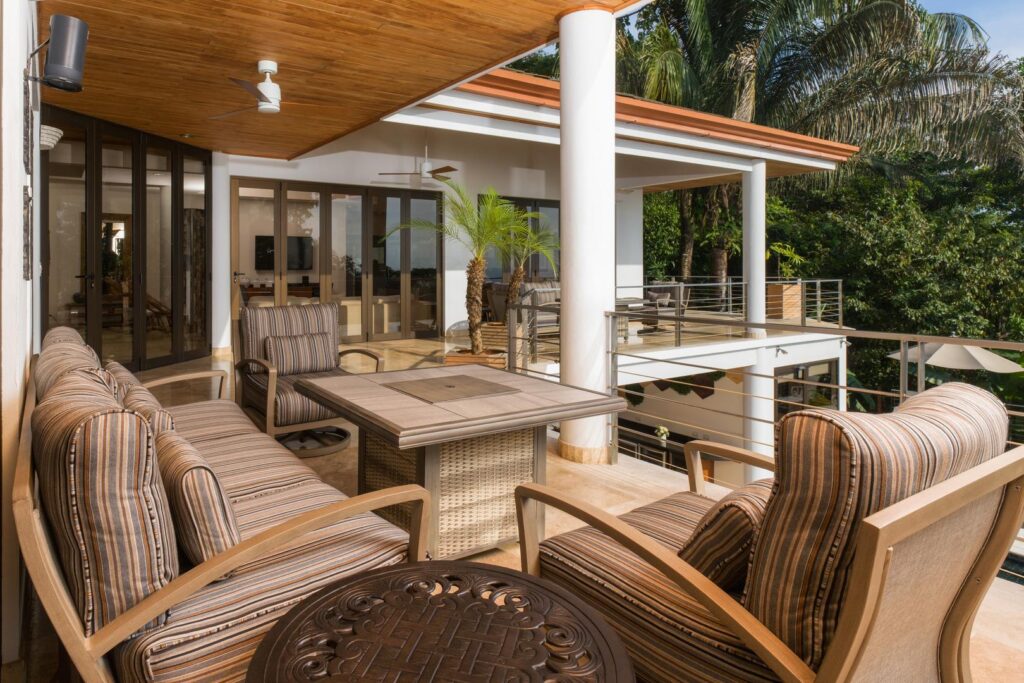 A relaxed outdoor lounge with shaded seating, warm wood accents, and soothing views of the tropical forest—an inviting spot to unwind throughout the day.