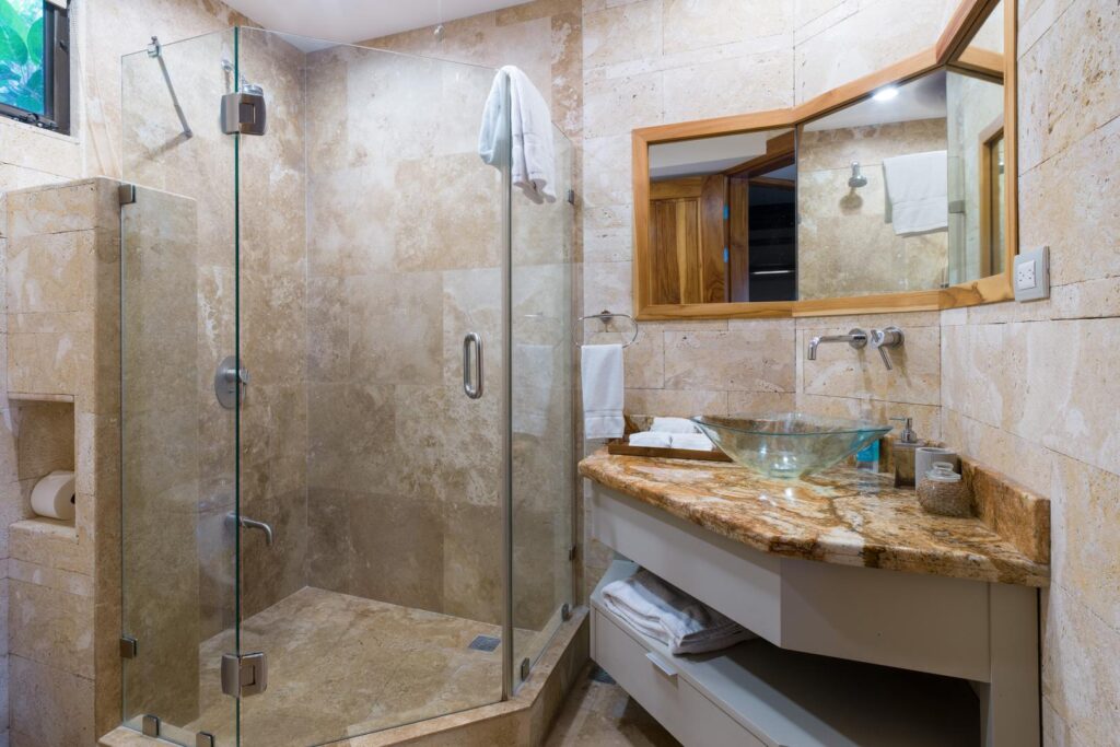 A soothing stone bathroom with a wide glass shower, organic textures, and a modern vessel sink that brings a tranquil, spa-inspired ambiance.