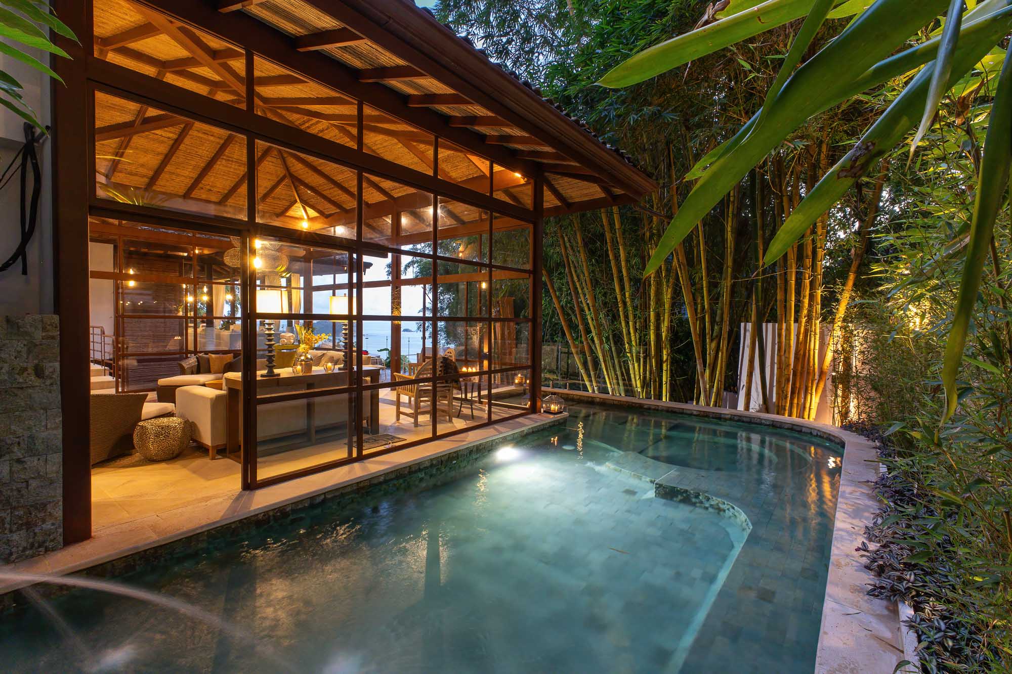 Private pool beside the new living wing at night with glass walls and bamboo surroundings in Manuel Antonio.