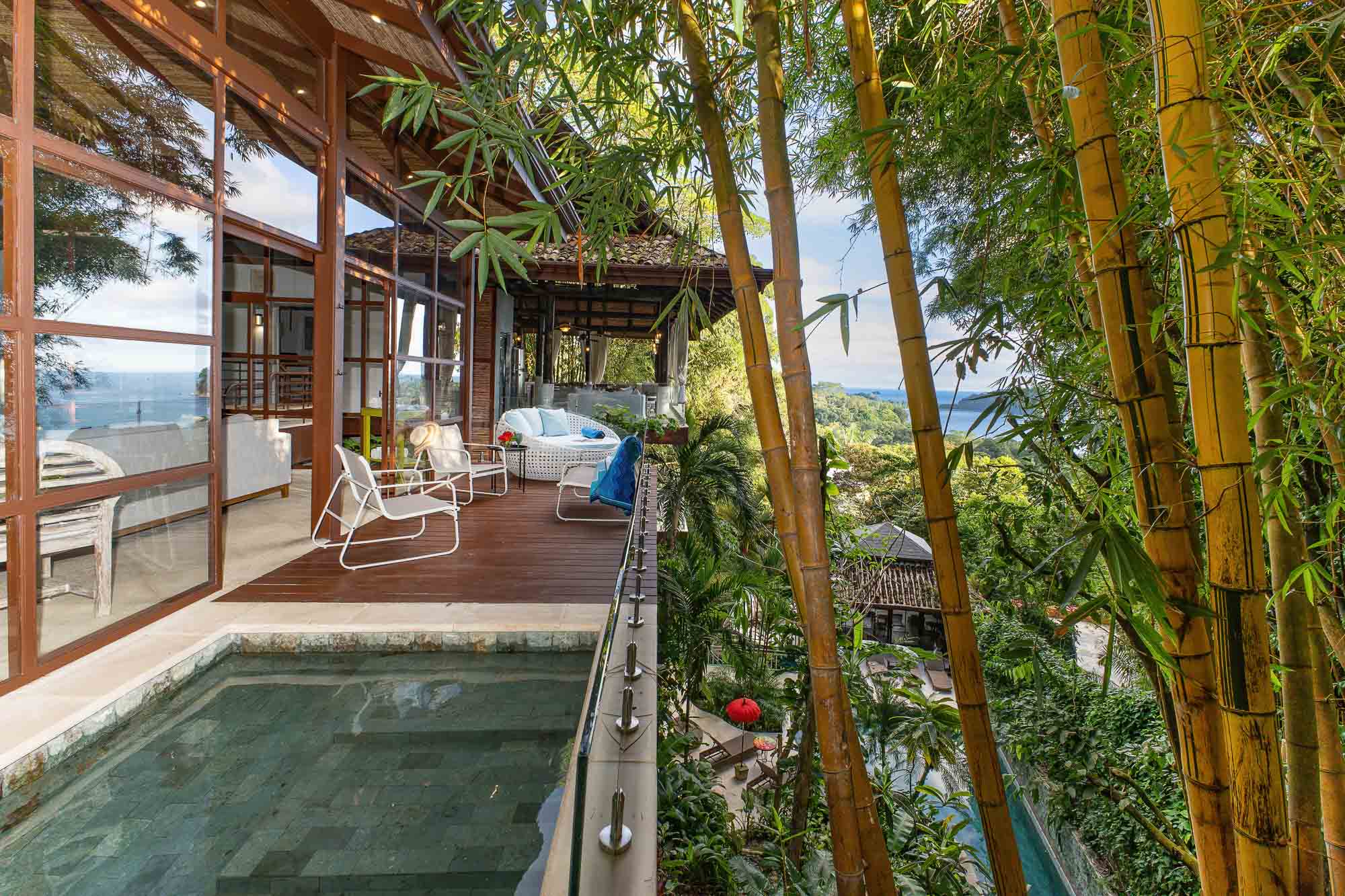 Terrace with plunge pool, outdoor seating, bamboo, and ocean views beyond the jungle.