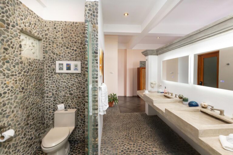 Large bathroom with stone walls, double sink vanity, and walk-in shower in Manuel Antonio Costa Rica