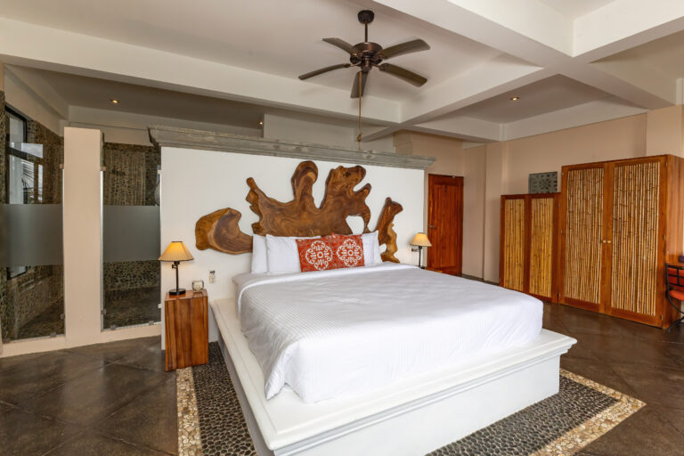 Master bedroom with king bed, wood accents, and ensuite bathroom in Manuel Antonio Costa Rica