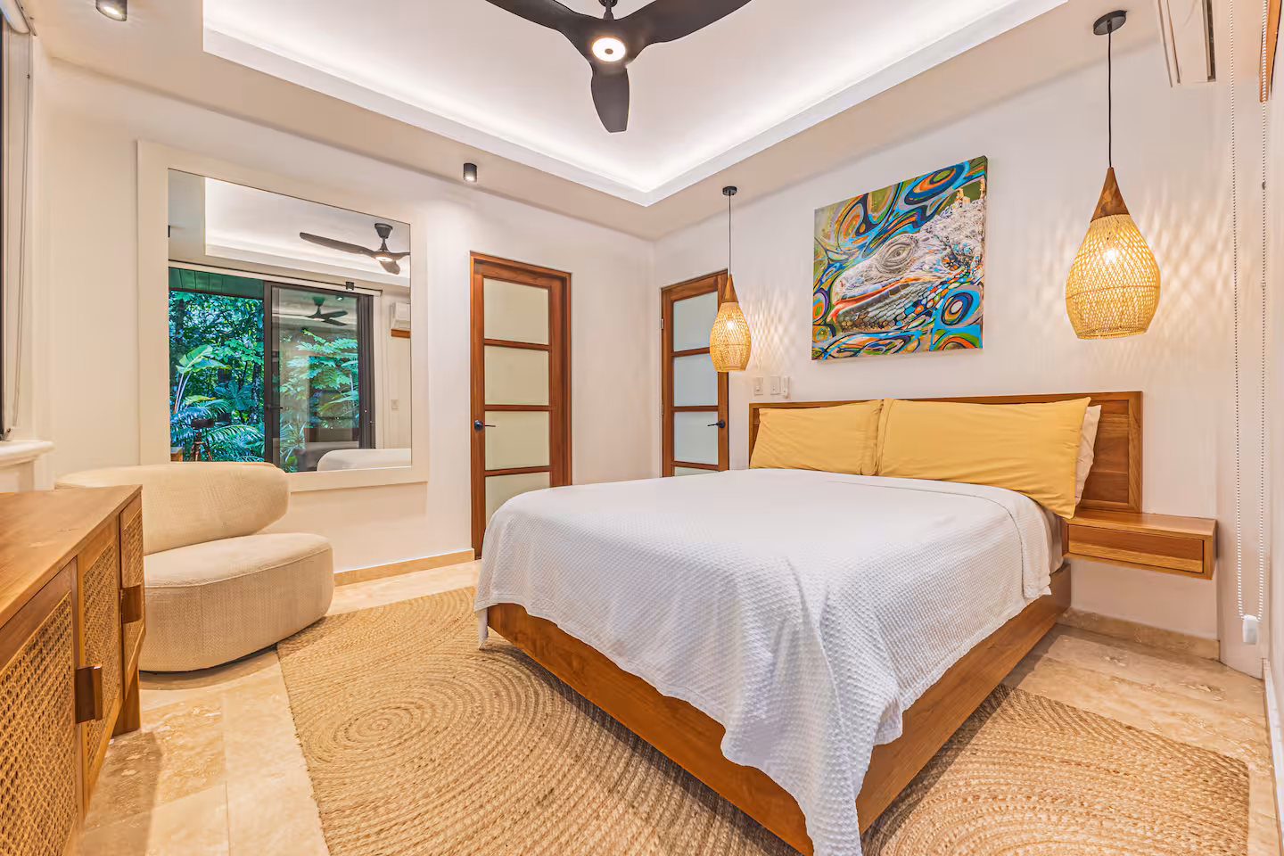Bedroom with wood furnishings, pendant lights, and large window overlooking tropical greenery near Dominical.