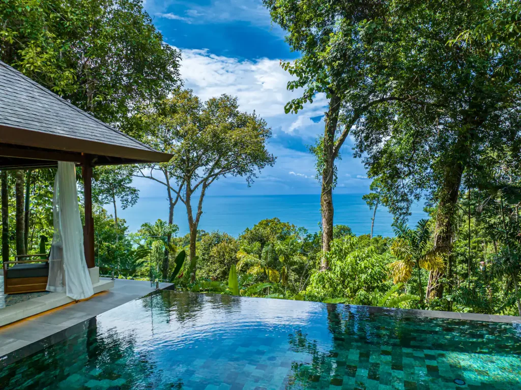 Infinity-edge pool surrounded by tropical jungle with ocean views near Dominical, Costa Rica.