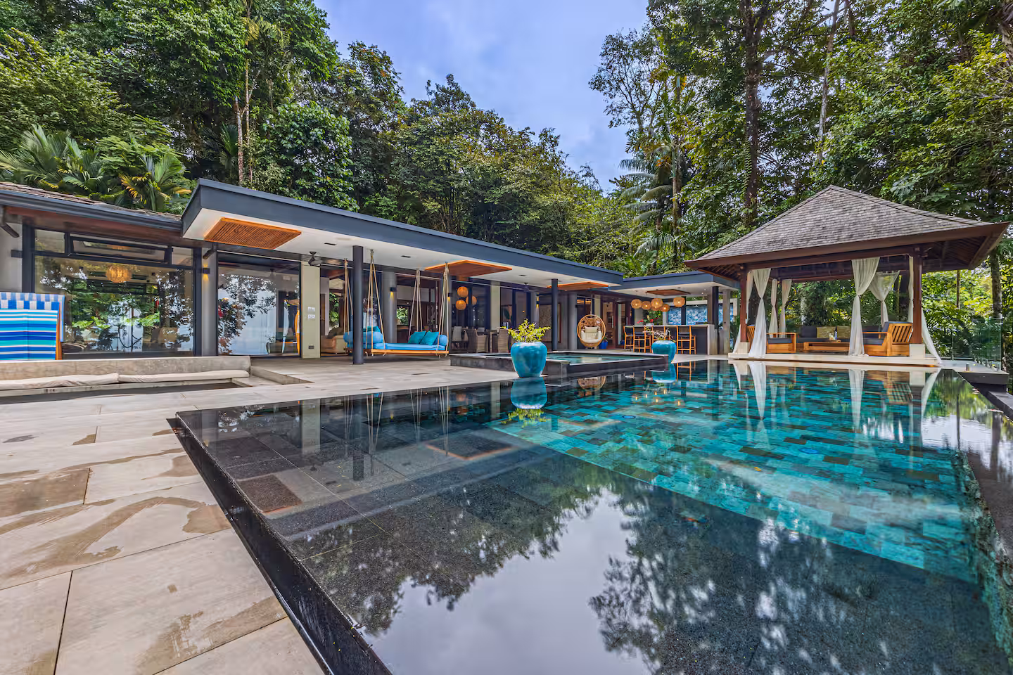 Infinity-edge pool with outdoor living areas and gazebo surrounded by tropical jungle at a luxury villa near Dominical, Costa Rica.