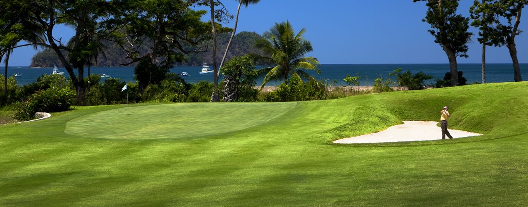 Golfer on oceanfront fairway at Los Sueños with Pacific Ocean views and tropical landscape.