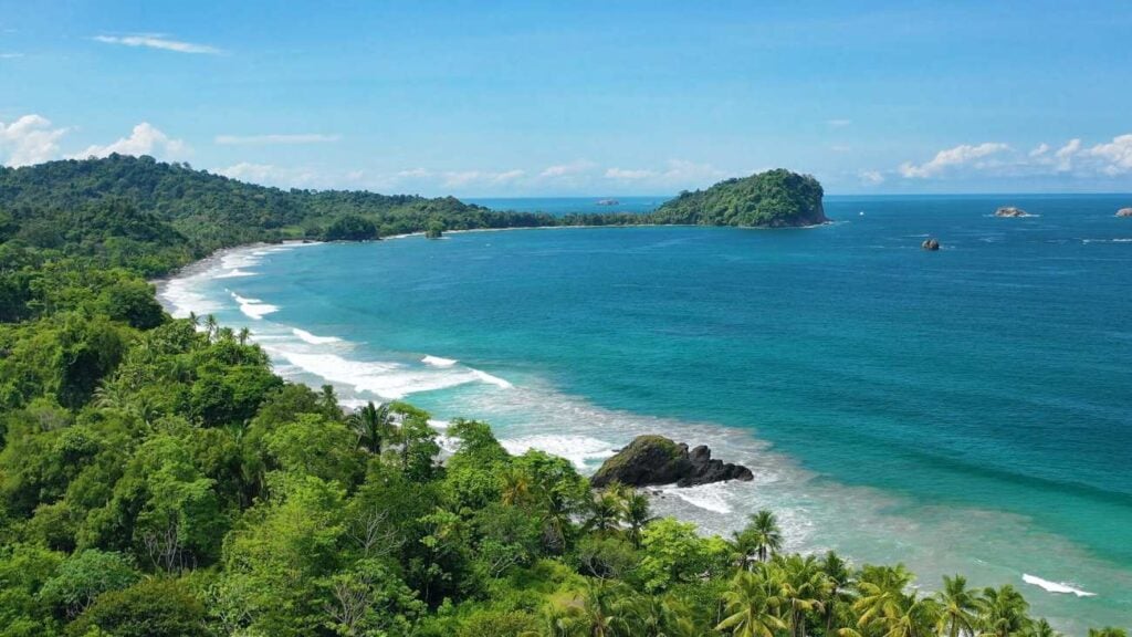 Aerial view of Manuel Antonio National Park's tropical coastline with rainforest, white sand beaches, and the Pacific Ocean in Costa Rica.