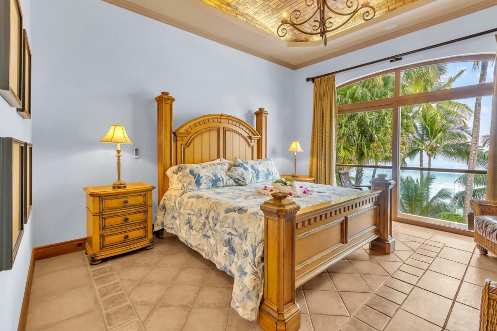 A spacious, serene bedroom with elegant wood details and views of the beach.