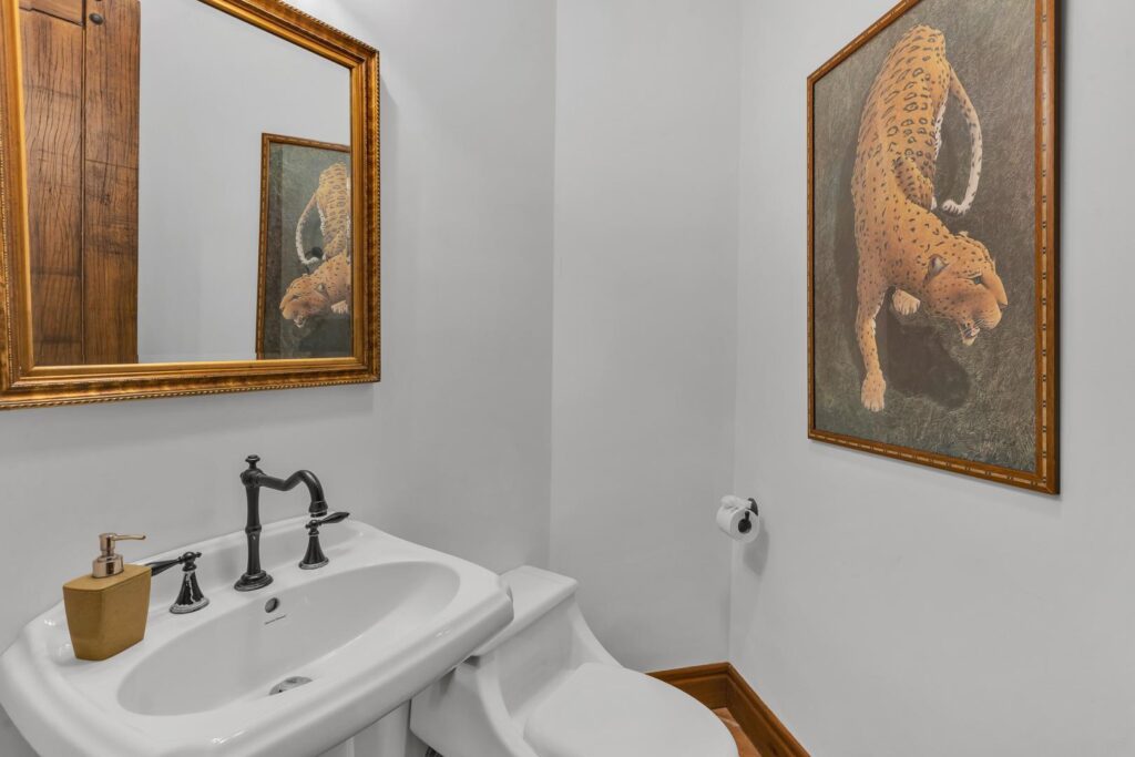 A neatly designed half-bath with classic finishes and tropical artwork.