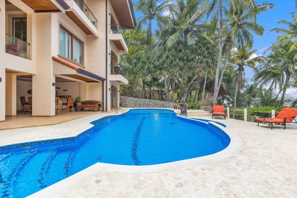 Sunny pool area with bright loungers, palm trees, and quick access to the beach.