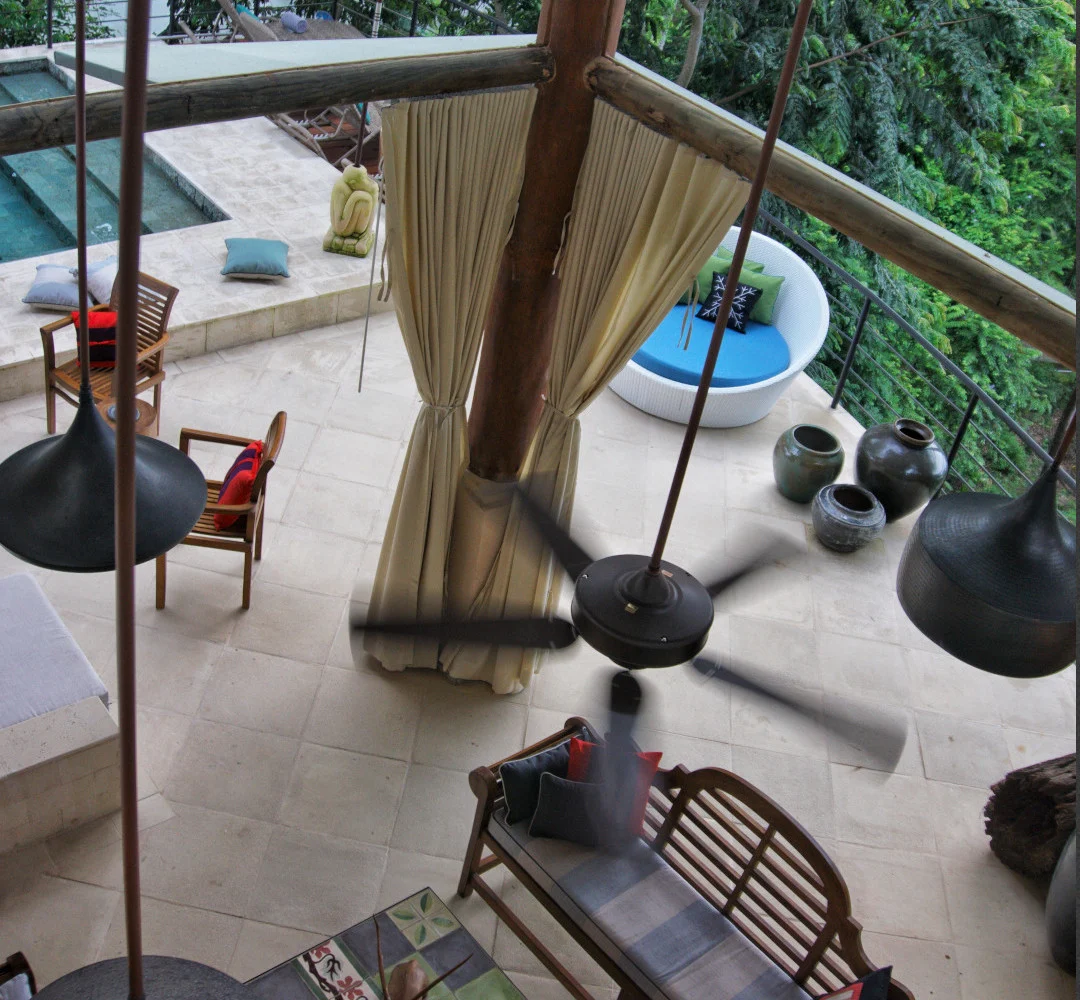 Elevated view of an open-air lounge with seating, flowing curtains, and lush treetop surroundings in Manuel Antonio